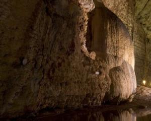 Spettacolare grotta illuminata con riflessi d'acqua e formazioni rocciose.