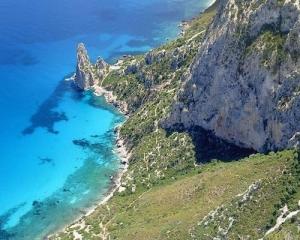 Scogliera spettacolare con mare cristallino e vegetazione rigogliosa.