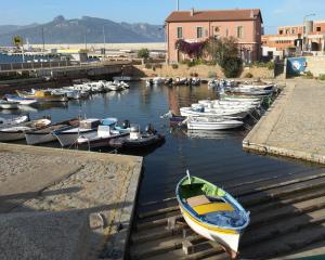 Piccolo porto con barche, edificio rosa e montagne sullo sfondo.