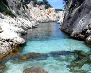 Acqua cristallina tra le rocce bianche di una caletta.