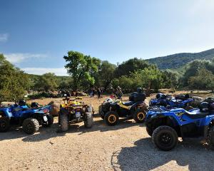 Quad parcheggiati in un'area naturale con alberi e colline.