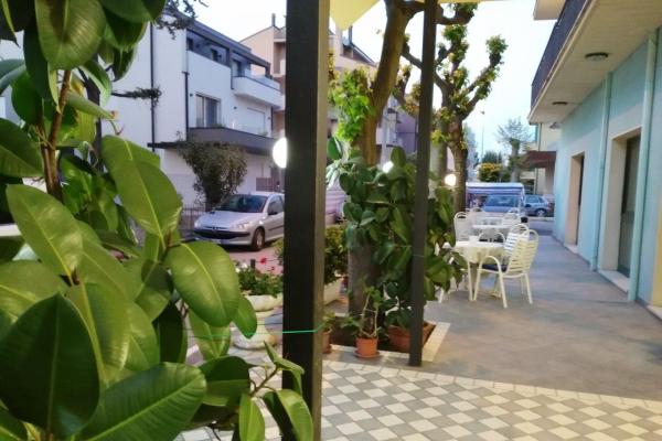 Giardino con tavoli bianchi e piante verdi in un'area residenziale.