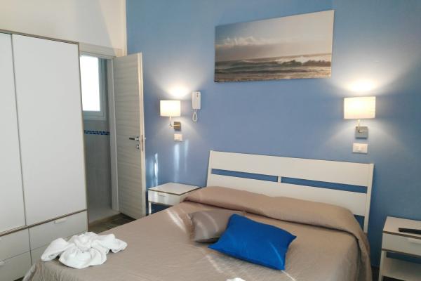 Camera moderna con pareti blu e arredi bianchi.