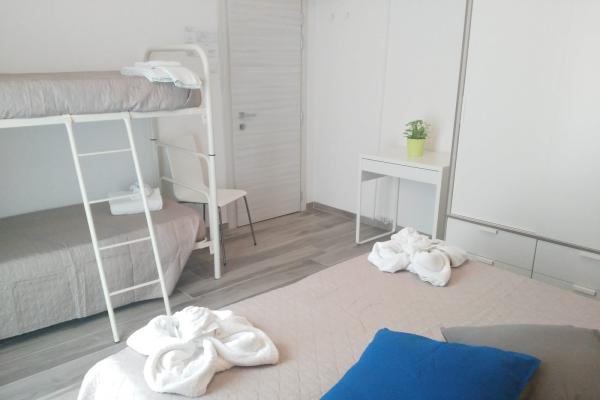 Camera moderna con letto matrimoniale e a castello, scrivania e pianta.