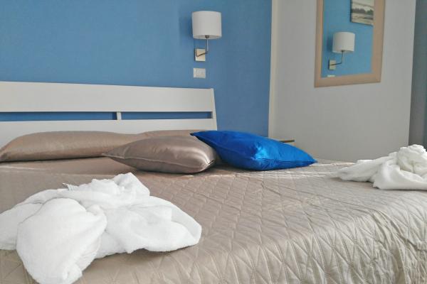 Camera da letto con parete blu e cuscini colorati.