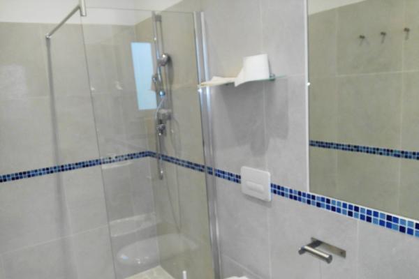 Bagno moderno con doccia e piastrelle blu.