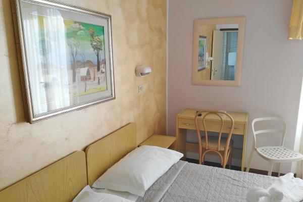 Camera accogliente con letto, scrivania e dipinto colorato sulla parete.