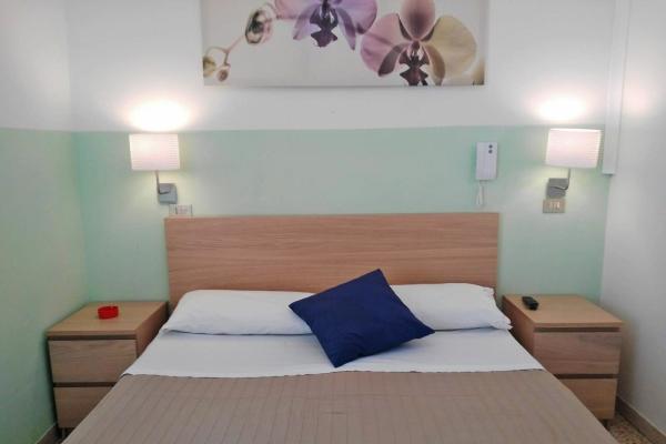Camera da letto con letto matrimoniale, comodini e luci soffuse.