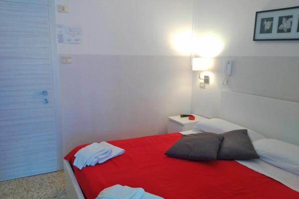Camera da letto con letto rosso e cuscini grigi.