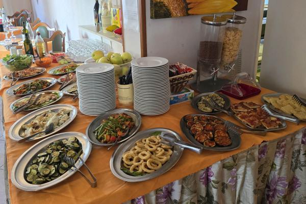 Buffet con piatti vari, verdure e pane, pronto per il servizio.