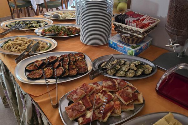 Buffet con pizza, focaccia e verdure grigliate.