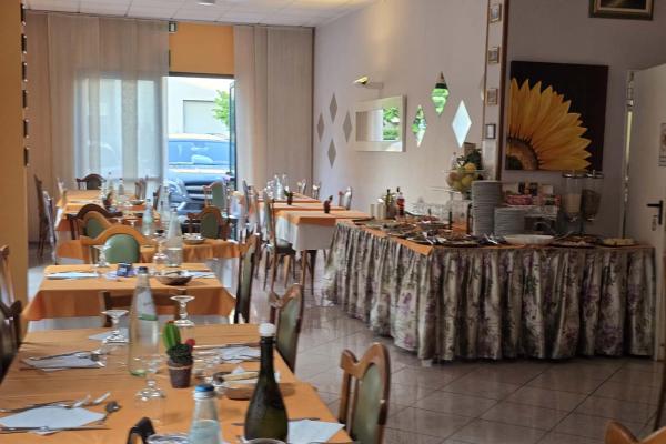 Ristorante accogliente, tavoli apparecchiati, buffet invitante, atmosfera calda e luminosa.