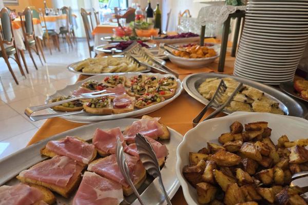 Un buffet invitante con affettati, bruschette e patate arrosto in un'atmosfera accogliente.