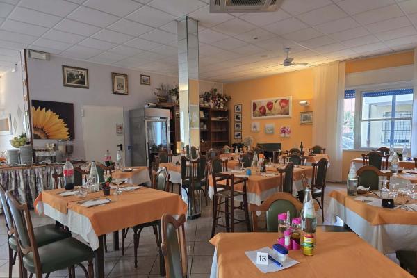 Ristorante accogliente con tavoli apparecchiati, atmosfera calda e decorazioni floreali.