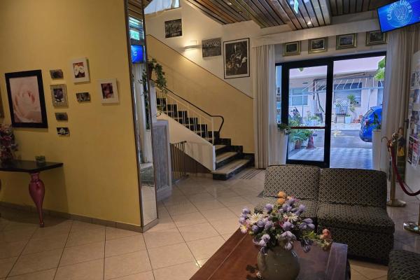Accogliente ingresso con divani, fiori e foto alle pareti.