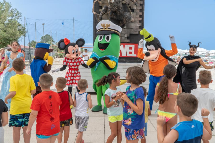 Glückliche Kinder tanzen mit bunten Figuren in einer fröhlichen, festlichen Atmosphäre.
