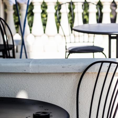 Metal tables and chairs on a sunny terrace.