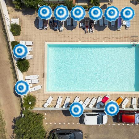 Piscina con ombrelloni blu e lettini, vista dall'alto.