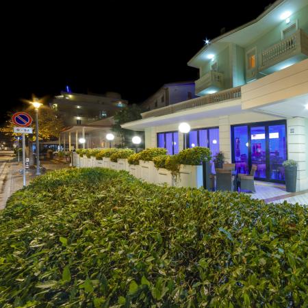 Modern hotel with night lighting, plants, and visible sign.