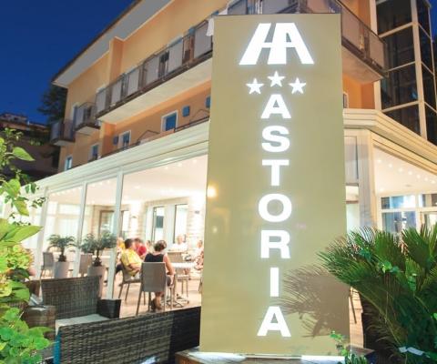 Hotel Astoria di notte con persone sedute all'interno.