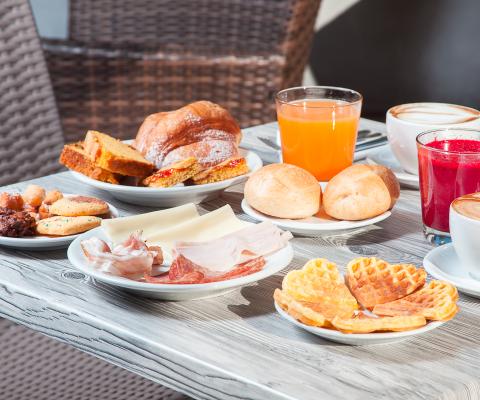 Colazione con dolci, salumi, formaggi, succhi e caffè.