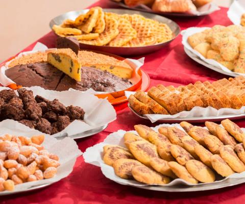 Varietà di dolci su tavolo rosso, tra cui biscotti e torte.