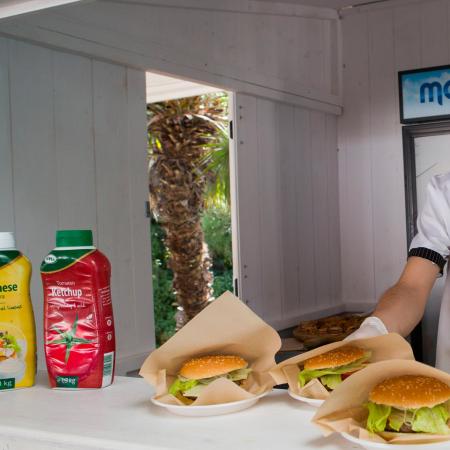 Cuoco sorridente serve hamburger e hot dog con entusiasmo e cordialità.