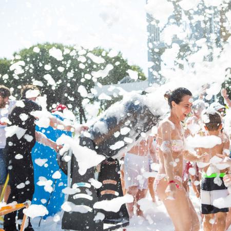 Festa di schiuma estiva, risate e gioia tra amici sotto il sole.
