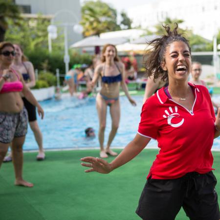 Donna sorridente guida ballo allegro a bordo piscina.