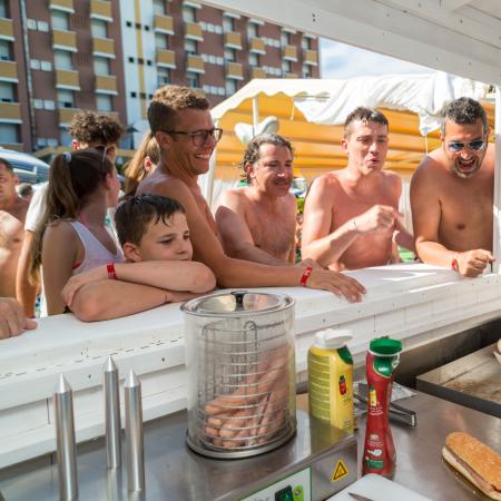 Persone felici in fila per hot dog in una giornata di sole.