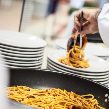 Chef serve spaghetti fumanti con passione, piatti bianchi pronti per il banchetto.