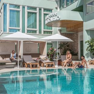 Pool with loungers, umbrellas, and people relaxing.