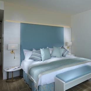 Modern room with bed, armchair, and TV.