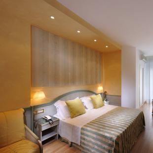 Modern hotel room with double bed and wall-mounted TV.