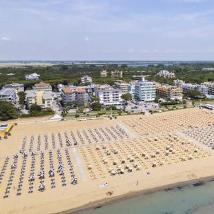 Beach with umbrellas and sea, surrounded by residential buildings.