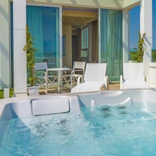 Terrace with jacuzzi, white chairs, and panoramic view.