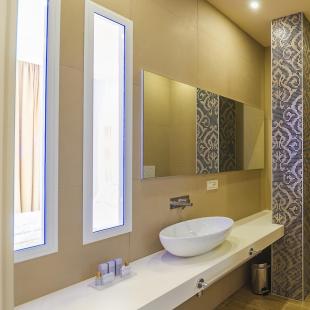 Modern bathroom with sink, bidet, and decorative mosaic.