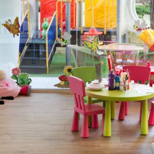 Colorful children's room with tables, chairs, and toys.