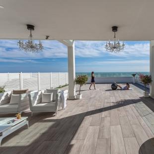Elegant terrace with sea view, white furniture, and plants.