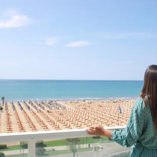 Woman gazes at the sea from a balcony.