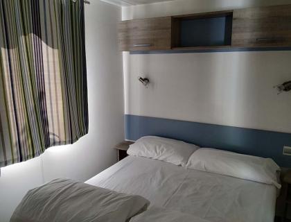 Camera accogliente con letto matrimoniale, tende a righe, atmosfera rilassante.