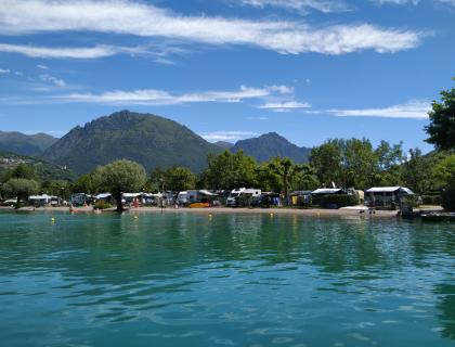 Montagna serena, lago blu, campeggio vivace, cielo limpido, natura rigogliosa.