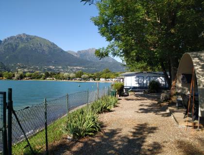 Vista su lago alpino con montagne e tenda, atmosfera serena e naturale.