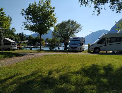 Camper sul lago, natura e montagne serene, atmosfera rilassante.