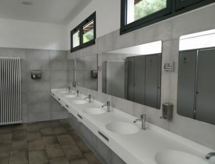 Bagno moderno e luminoso con lavandini bianchi e specchi ampi.