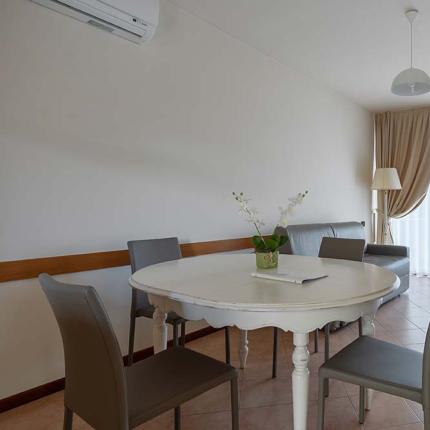 Bright living room with round table, chairs, and beige curtains.