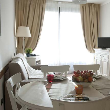 Bright dining room with round table, sofa, and TV.