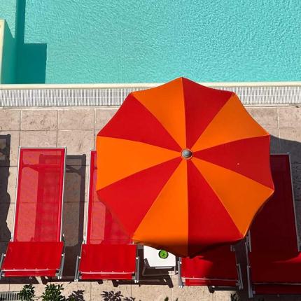 Orange and red umbrella near a swimming pool.