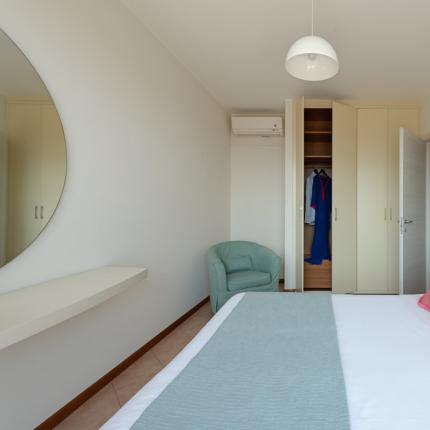 Bright bedroom with open closet and pink pillows on the bed.