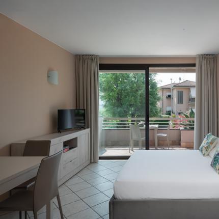 Camera moderna con letto, TV e balcone con vista.